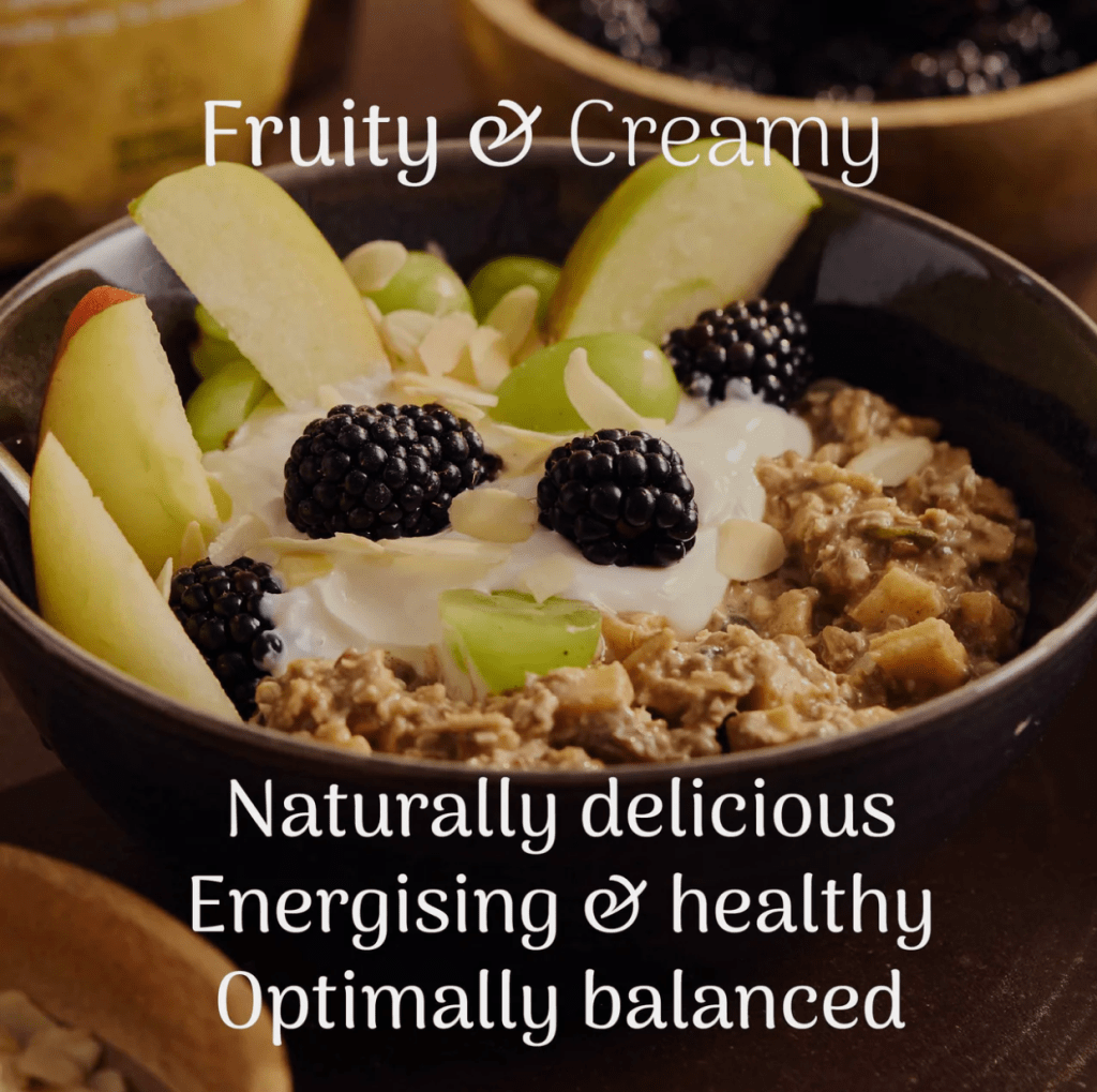 A bowl of Veloforte Overnight Oats topped with slices of green apple, blackberries, and toasted almonds, with a dollop of Greek yogurt, all set against a dark background.